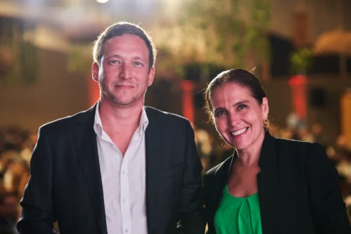 Registro social de asistentes y momentos humanos en evento corporativo. Dos asistentes sonriendo durante un evento corporativo con ambiente de salón