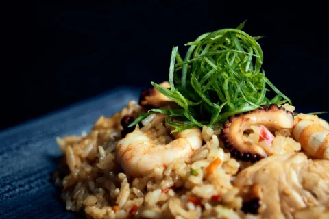 Fotografía gastronómica con fondo oscuro para restaurantes, cartas digitales y contenido comercial. Fotografía gastronómica de plato con mariscos, arroz y vegetales sobre fondo oscuro