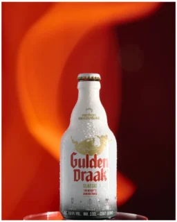 Fotografía comercial de producto con iluminación de estudio y composición premium. Fotografía profesional de botella de bebida premium con iluminación de estudio y fondo naranja